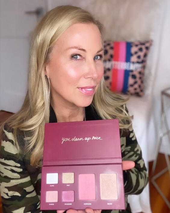 Woman holding a makeup colour palette of four eyeshadows, a warm blush, an illuminating highlighter